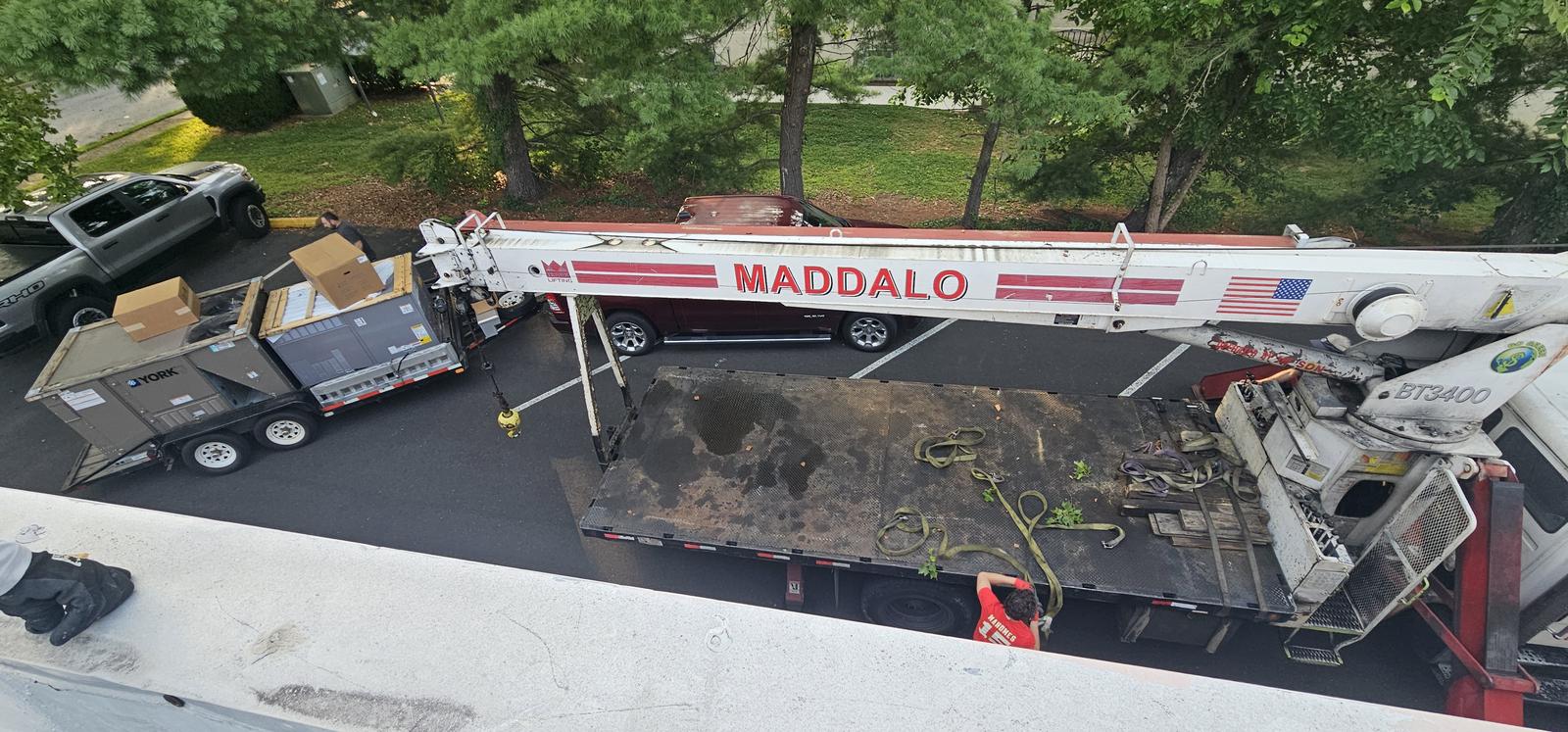 Crane truck and flatbed staged to remove an old rooftop HVAC unit